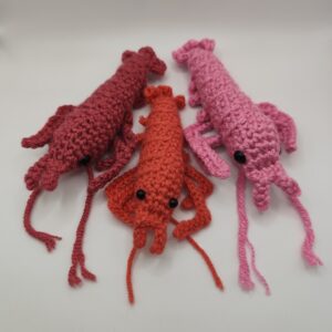 trois peluches crevettes en crochet sur fond blanc